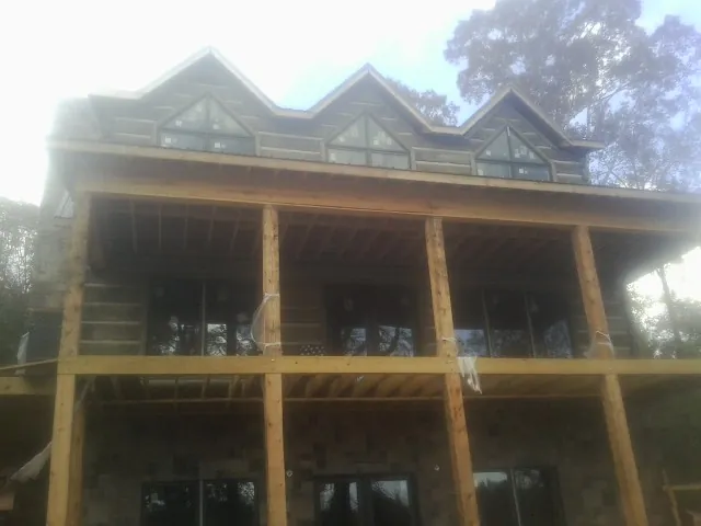 Dormers and porch framing on a large log home under construction — Roof Coating work by our crew in Jackpot