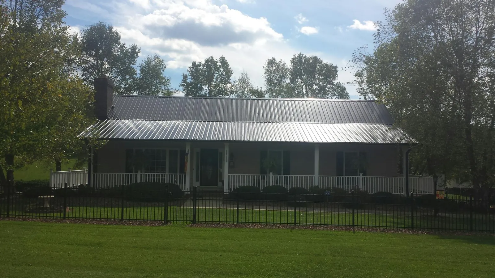 Gray metal roof on a brick ranch with a full width front porch — Gutter Guard Installation work by our crew in Jackpot